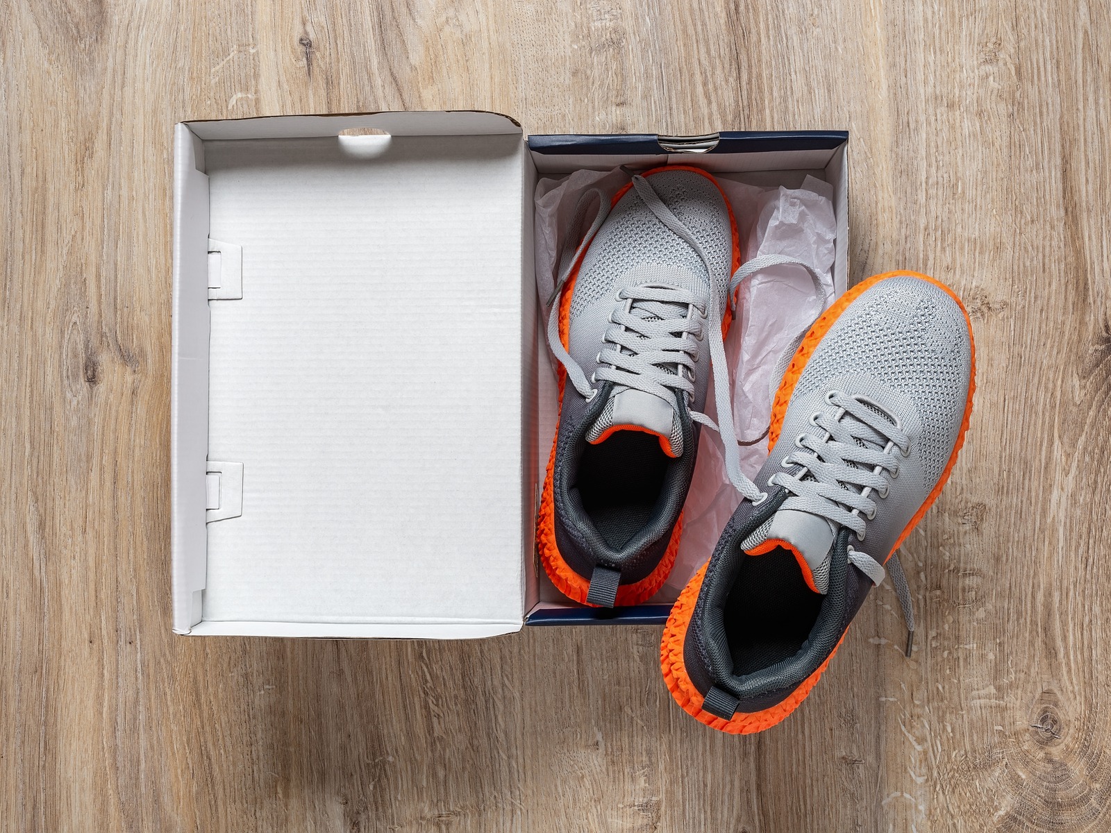 A box with the lid open, revealing a pair of new running shoes inside.