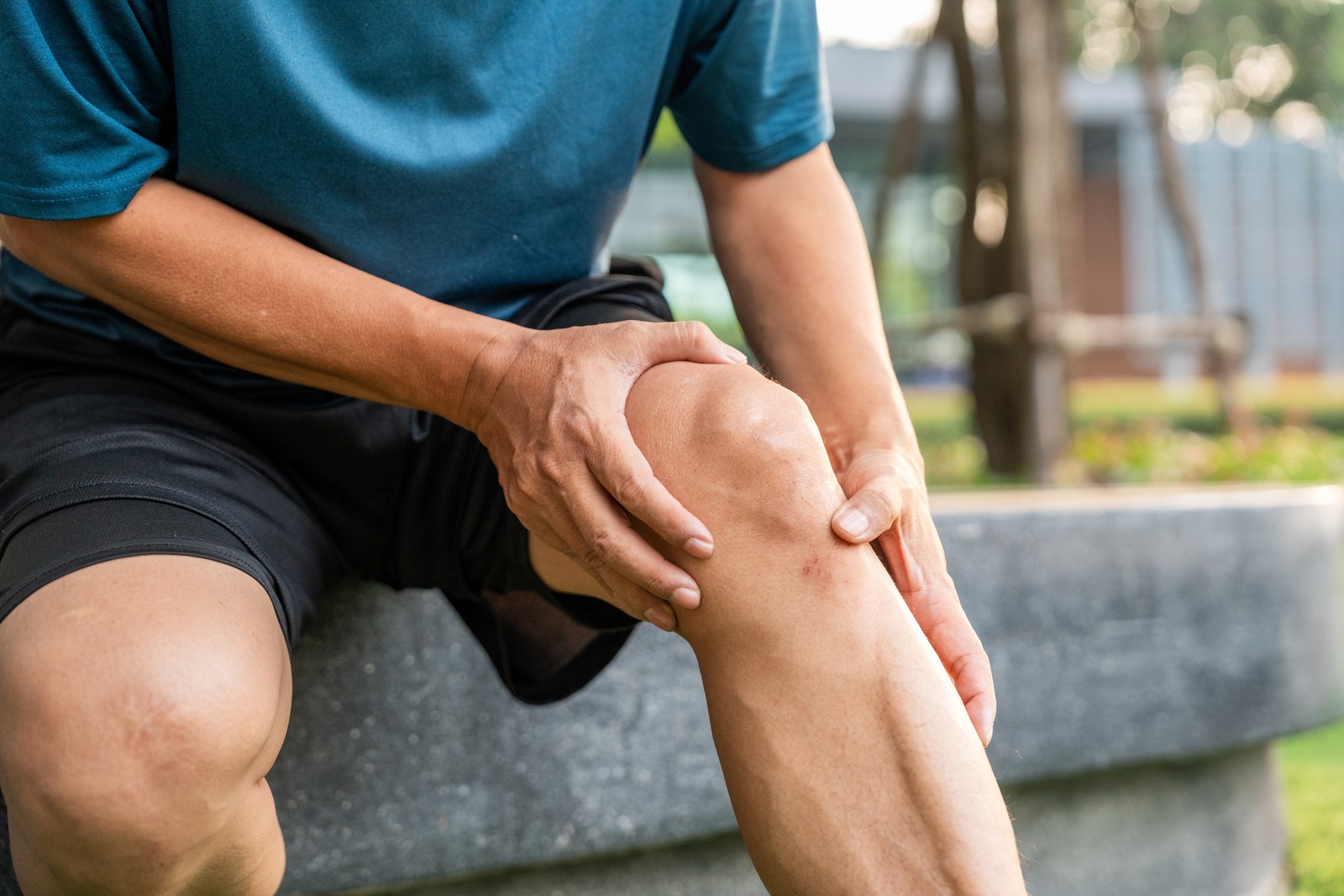 Seated runner holding their injured knee.