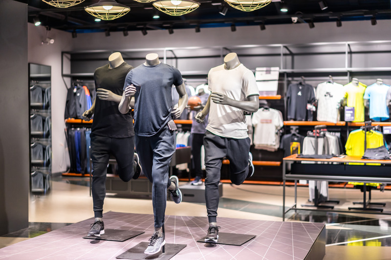 Mannequins posed in dynamic running stances, showcasing athletic apparel and footwear in a retail store.